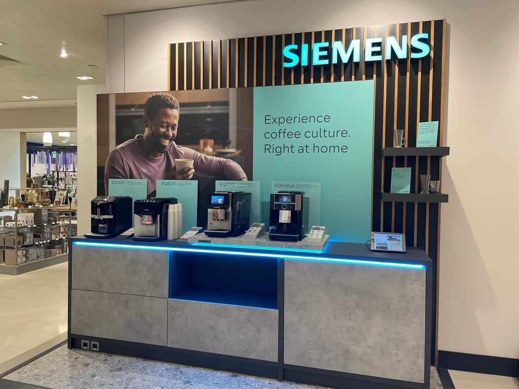 Siemens EQ coffee machine barista display island unit at John Lewis Cambridge — dark oak veneer finish with integrated product staging